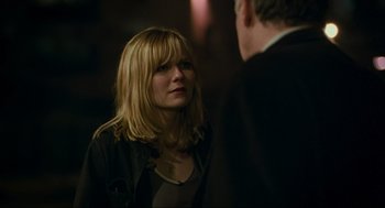Movie still from “Eternal Sunshine of the Spotless Mind” (2004), directed by Michel Gondry – A woman with blonde hair and a black jacket is talking to a man in a black suit; Close Up shot, Over the shoulder angle