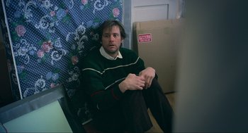 Movie still from “Eternal Sunshine of the Spotless Mind” (2004), directed by Michel Gondry – A man sitting on the floor next to boxes; Medium shot, High angle
