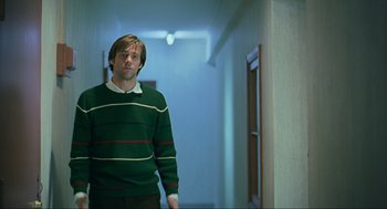 Movie still from “Eternal Sunshine of the Spotless Mind” (2004), directed by Michel Gondry – A man standing in a hallway wearing a green sweater; Medium shot, Low angle