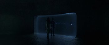 Movie still from “Eternals” (2021), directed by Chloé Zhao – Two people are standing in front of an illuminated wall; Extreme Wide shot, High angle