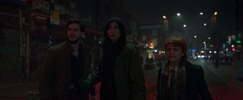 Movie still from “Eternals” (2021), directed by Chloé Zhao – A group of people standing next to each other on a street; Medium shot, High angle