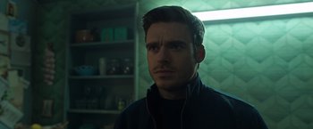 Movie still from “Eternals” (2021), directed by Chloé Zhao – A person wearing a jacket in a room; Close Up shot, Over the shoulder angle