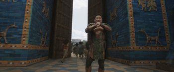 Movie still from “Eternals” (2021), directed by Chloé Zhao – A man dressed as a roman soldier standing in front of a doorway; Medium shot, High angle