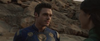 Movie still from “Eternals” (2021), directed by Chloé Zhao – A person wearing a costume near a rock wall; Close Up shot, Over the shoulder angle