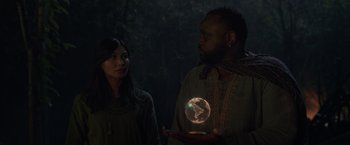 Movie still from “Eternals” (2021), directed by Chloé Zhao – A man and a woman standing next to each other holding a globe; Medium shot, Low angle