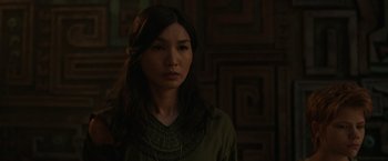 Movie still from “Eternals” (2021), directed by Chloé Zhao – A woman with long dark brown hair wearing a green shirt; Close Up shot, Over the shoulder angle