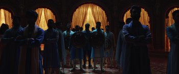Movie still from “Eternals” (2021), directed by Chloé Zhao – A group of men standing next to each other holding shields; Extreme Wide shot, Low angle