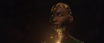 Movie still from “Eternals” (2021), directed by Chloé Zhao – A woman with glowing yellow eyes is wearing a green and gold outfit; Extreme Close Up shot, Low angle