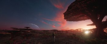 Movie still from “Eternals” (2021), directed by Chloé Zhao – A person standing in front of a large rock formation; Extreme Wide shot, Over the shoulder angle
