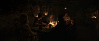 Movie still from “Eternals” (2021), directed by Chloé Zhao – A group of people sitting around a table with candles; Wide shot, High angle