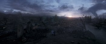 Movie still from “Eternals” (2021), directed by Chloé Zhao – Two people are standing in the middle of a destroyed field; Extreme Wide shot, High angle
