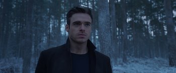 Movie still from “Eternals” (2021), directed by Chloé Zhao – A man standing in front of some trees in the woods; Close Up shot, Over the shoulder angle