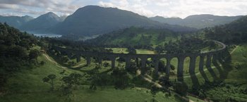 Movie still from “Eternals” (2021), directed by Chloé Zhao – An aerial view of a bridge in the middle of a green valley; Extreme Wide shot, High angle