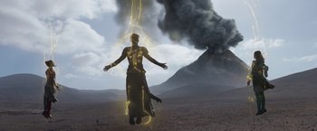 Movie still from “Eternals” (2021), directed by Chloé Zhao – A man standing in front of a smoke filled sky; Extreme Wide shot, Low angle