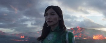 Movie still from “Eternals” (2021), directed by Chloé Zhao – A woman in a green outfit standing in front of a mountain; Close Up shot, Low angle