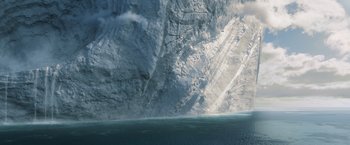 Movie still from “Eternals” (2021), directed by Chloé Zhao – A view of the ocean from a boat in front of a large cliff; Extreme Wide shot, Overhead angle