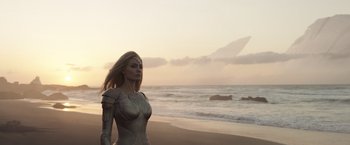 Movie still from “Eternals” (2021), directed by Chloé Zhao – A woman standing on a beach near the ocean; Medium shot, Low angle