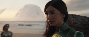 Movie still from “Eternals” (2021), directed by Chloé Zhao – A woman with long hair is standing on the beach; Close Up shot, Over the shoulder angle