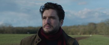 Movie still from “Eternals” (2021), directed by Chloé Zhao – A person wearing a scarf and a jacket; Close Up shot, Low angle