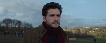 Movie still from “Eternals” (2021), directed by Chloé Zhao – A person wearing a jacket and a scarf; Close Up shot, Low angle