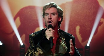 Movie still from “Eurovision Song Contest: The Story of Fire Saga” (2020), directed by David Dobkin – A man with a beard is singing into a microphone; Close Up shot, Over the shoulder angle