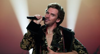 Movie still from “Eurovision Song Contest: The Story of Fire Saga” (2020), directed by David Dobkin – A man with a microphone in his mouth; Medium shot, Over the shoulder angle