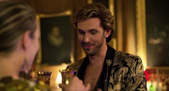 Movie still from “Eurovision Song Contest: The Story of Fire Saga” (2020), directed by David Dobkin – A man in a black and gold jacket holding a glass of wine; Close Up shot, Over the shoulder angle