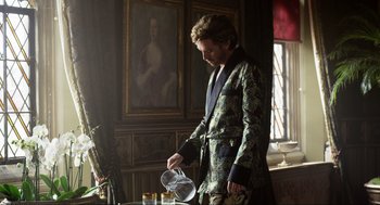 Movie still from “Eurovision Song Contest: The Story of Fire Saga” (2020), directed by David Dobkin – A man in a dressing gown pouring a glass of wine; Medium shot, Over the shoulder angle