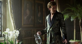 Movie still from “Eurovision Song Contest: The Story of Fire Saga” (2020), directed by David Dobkin – A man in a suit holding a pitcher of water; Medium shot, Low angle