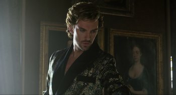 Movie still from “Eurovision Song Contest: The Story of Fire Saga” (2020), directed by David Dobkin – A man with long hair wearing a black and gold robe; Close Up shot, Over the shoulder angle