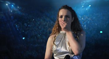 Movie still from “Eurovision Song Contest: The Story of Fire Saga” (2020), directed by David Dobkin – A woman covering her mouth with her hands; Close Up shot, Over the shoulder angle