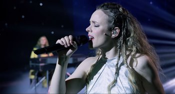 Movie still from “Eurovision Song Contest: The Story of Fire Saga” (2020), directed by David Dobkin – A woman is holding a microphone up to her mouth; Close Up shot, Low angle