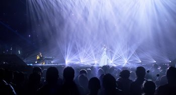Movie still from “Eurovision Song Contest: The Story of Fire Saga” (2020), directed by David Dobkin – A woman in a white dress on a stage with a microphone; Extreme Wide shot, High angle