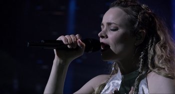 Movie still from “Eurovision Song Contest: The Story of Fire Saga” (2020), directed by David Dobkin – A woman singing into a microphone on a stage; Close Up shot, Low angle