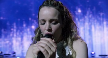 Movie still from “Eurovision Song Contest: The Story of Fire Saga” (2020), directed by David Dobkin – A woman is holding a microphone up to her mouth; Close Up shot, Low angle