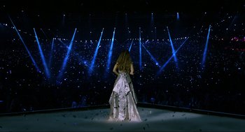 Movie still from “Eurovision Song Contest: The Story of Fire Saga” (2020), directed by David Dobkin – A woman standing in front of an audience on a stage; Extreme Wide shot, High angle
