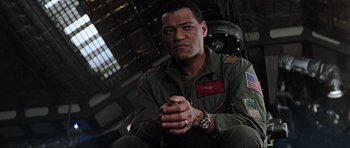 Movie still from “Event Horizon” (1997), directed by Paul W.S. Anderson – A man sitting in a chair with his hands clasped together; Close Up shot, Low angle