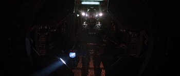 Movie still from “Event Horizon” (1997), directed by Paul W.S. Anderson – A man standing in a dark room with a helmet on; Wide shot, Overhead angle