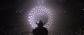 Movie still from “Event Horizon” (1997), directed by Paul W.S. Anderson – A person in a helmet is standing in front of lights; Extreme Wide shot, Low angle