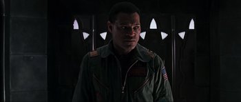 Movie still from “Event Horizon” (1997), directed by Paul W.S. Anderson – A man in a green jacket is standing in a dark room; Close Up shot, Low angle