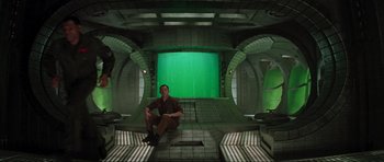 Movie still from “Event Horizon” (1997), directed by Paul W.S. Anderson – A man sitting in a room with a green screen in the background; Wide shot, High angle