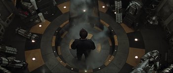 Movie still from “Event Horizon” (1997), directed by Paul W.S. Anderson – A man standing in the middle of a circle of smoke coming out; Wide shot, Overhead angle