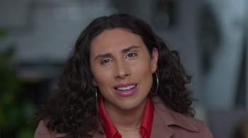 Movie still from “Every Body” (2023), directed by Julie Cohen – A man with long hair and a red shirt; Close Up shot, Over the shoulder angle
