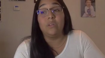 Movie still from “Every Body” (2023), directed by Julie Cohen – A woman wearing glasses and a white t - shirt; Close Up shot, Low angle