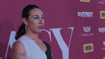 Movie still from “Every Body” (2023), directed by Julie Cohen – A woman in a black and white dress with a tattoo on her arm; Close Up shot, Low angle