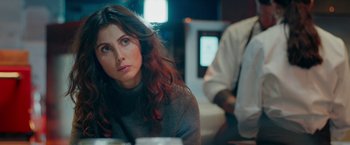 Movie still from “A Taste of Hunger” (2021), directed by Christoffer Boe – A woman sitting in front of a television; Close Up shot, Over the shoulder angle