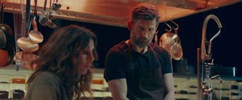 Movie still from “A Taste of Hunger” (2021), directed by Christoffer Boe – A man and a woman are standing in a kitchen; Medium shot, Over the shoulder angle