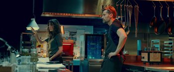 Movie still from “A Taste of Hunger” (2021), directed by Christoffer Boe – A man and a woman are standing in a kitchen; Medium shot, Low angle