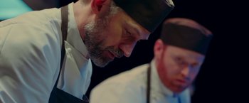 Movie still from “A Taste of Hunger” (2021), directed by Christoffer Boe – A man with a beard wearing a black hat; Close Up shot, Low angle