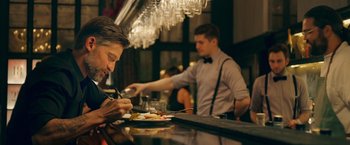 Movie still from “A Taste of Hunger” (2021), directed by Christoffer Boe – A man sitting at a table with a plate in front of him; Medium shot, Over the shoulder angle